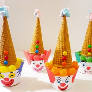 Könnte beinhalten: Vier Clown-Cupcakes, verziert mit Waffelhörnchen, Süßigkeiten und buntem Frosting. Jeder Cupcake hat ein anderes farbiges Clown-Gesicht.