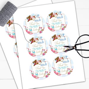 May include: Six round thank you stickers with a whimsical Alice in Wonderland theme. The stickers feature illustrations of Alice and the Mad Hatter, with a blue and white background and gold accents. The text on the stickers reads "Thank You for coming to my party, [Name]"