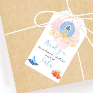May include: A white thank you tag with a blue and pink watercolor illustration of a carriage. The text reads "Thank you for making my birthday magical! Lulu".