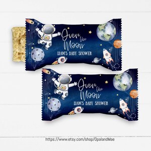 Może przedstawiać: Niebieski i biały papier do owijania batonów z astronautą, planetami i gwiazdami. Tekst brzmi "Over the Moon Liam's Baby Shower".