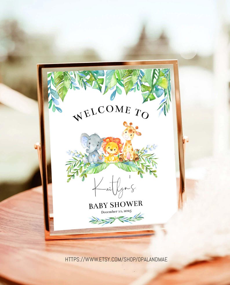 May include: A welcome sign for a baby shower with a jungle theme. The sign features a green leafy border with a giraffe, lion, and elephant. The text reads "Welcome to Kaitlyn's Baby Shower December 11, 2023".