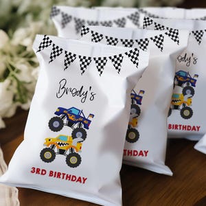 May include: White treat bags with a checkered flag banner design. The bags feature a blue and yellow monster truck design with the text "Brody's 3rd Birthday".