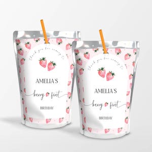 May include: Two pink and white juice pouches with a strawberry pattern. The pouches have a white label with the text "Amelia's Berry First Birthday" and a strawberry graphic.