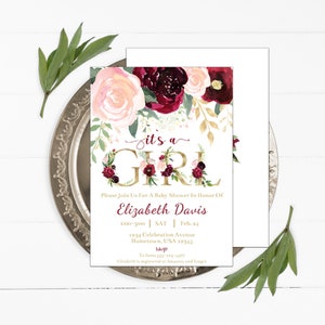 May include: A baby shower invitation with a floral design in shades of pink, red, and gold. The text reads "it's a girl" in gold lettering and includes the name "Elizabeth Davis" and details for the event.