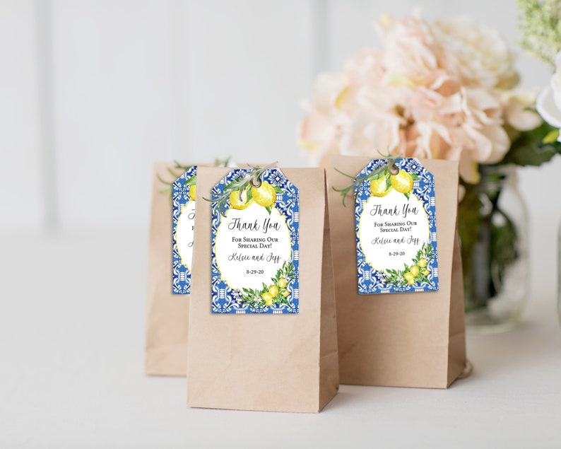 May include: Brown paper gift bags with decorative tags. The tags feature a blue and white tile design, lemons, and the text "Thank You For Sharing Our Special Day!" with names and a date.