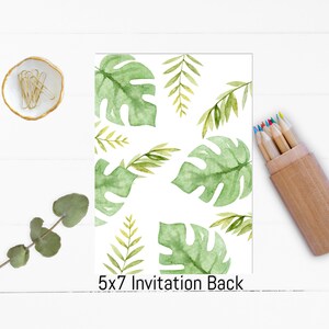 May include: A 5x7 invitation back with a watercolor design of green tropical leaves on a white background. A small dish with gold paper clips, a sprig of eucalyptus, and a wooden pencil holder with colored pencils are also visible.