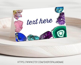 May include: A white card with a border of colourful gemstones. The text "text here" is printed in blue on the card.