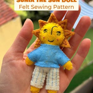 May include: A small felt doll shaped like a sun with a yellow face, orange rays, a blue shirt, and white pants with blue vertical stitching. The text SUNIA THE SUN DOLL Felt Sewing Pattern is displayed above the doll in orange and brown letters.