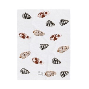 May include: A white rectangular textile featuring a repeating pattern of various brown and black seashell illustrations scattered across the surface. The fabric includes the small printed text Papa Piko near the bottom center of the design.