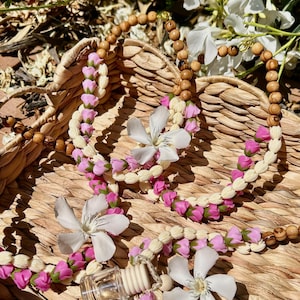 Peut inclure: Un accessoire de suspension pour diffuseur de voiture composé d'un petit flacon en verre transparent avec un bouchon en bois, enfilé sur une guirlande de perles en bois naturel, de perles texturées crème et de petites perles roses en bouton de rose.