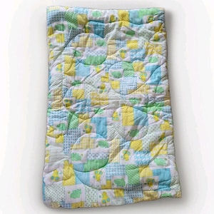 May include: A patchwork baby blanket with a quilted design. The blanket is made up of squares of white, yellow, blue, and green fabric. The design includes repeating patterns of teddy bears and elephants. The blanket is soft and appears to be made of cotton.