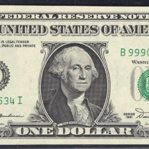 May include: A United States one-dollar bill. The note features a portrait of George Washington and is printed in green and black ink. Text includes "THE UNITED STATES OF AMERICA" and "ONE DOLLAR". The serial number is visible.