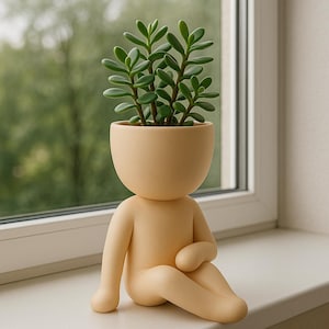 Könnte beinhalten: Beige Keramik-Pflanzgefäß in Form einer Person, mit einem kopfartigen Topf, der eine grüne Sukkulentenpflanze enthält. Die Figur sitzt mit angewinkelten Armen und Beinen. Der Pflanztopf steht auf einer weißen Fensterbank mit verschwommenem grünem Hintergrund.