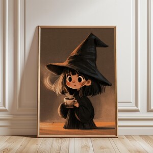 Op de afbeelding: Een ingelijste wandkunstprint met een gestileerde illustratie van een jong personage met donker haar, een grote, puntige zwarte heksenhoed en een zwarte mantel, die een dampende kop koffie of thee vasthoudt tegen een gedempte bruine achtergrond.