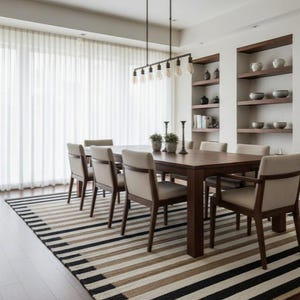 May include: A dining room featuring a dark wood table and six chairs. A rug with black, beige, and cream stripes lies beneath the table. A light fixture with exposed bulbs hangs above. Shelves on the wall display decorative items. The room has a modern design.