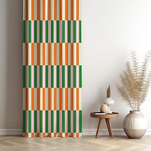 May include: A patterned curtain with vertical stripes in orange, green, pink, and cream. The curtain is hanging in front of a white wall. A small wooden side table and decorative vases are to the right of the curtain.