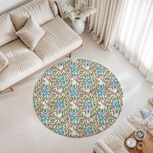Könnte beinhalten: Ein runder Teppich mit einem sich wiederholenden Muster aus blauen Schlangen, die mit grünen Blättern und kleinen rosa Blüten auf einem cremefarbenen Hintergrund verschlungen sind. Das Design bedeckt die gesamte runde Fläche des Teppichs.