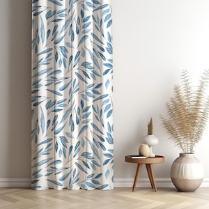 Puede incluir: Una cortina blanca con un patrón repetido de hojas azules de acuarela. La cortina cuelga frente a una pared blanca. Una pequeña mesa auxiliar de madera y jarrones decorativos con plantas secas están a la derecha de la cortina.