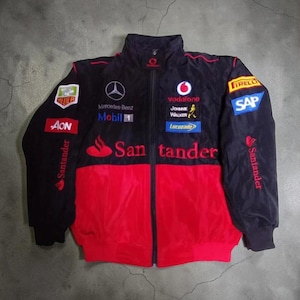 May include: Black and red racing jacket with multiple sponsor logos, including Mercedes-Benz, Vodafone, and Santander. The jacket has a zip-up front, a high collar, and various patches and embroidered details. The jacket is a blend of black and red.