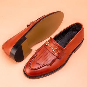 Handmade brown leather fringe loafers for men with metal bit detail, premium slip-on formal dress shoes crafted from genuine leather for weddings and business wear.