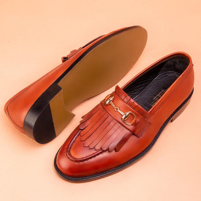 Handmade brown leather fringe loafers for men with metal bit detail, premium slip-on formal dress shoes crafted from genuine leather for weddings and business wear.