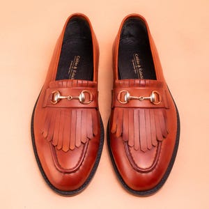 Handmade brown leather fringe loafers for men with metal bit detail, premium slip-on formal dress shoes crafted from genuine leather for weddings and business wear.
