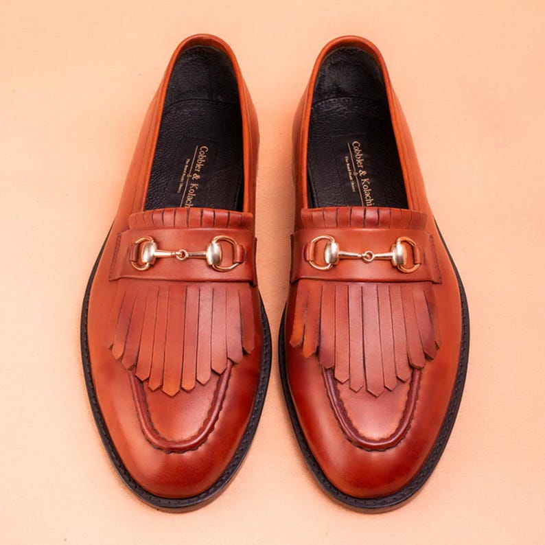 Handmade brown leather fringe loafers for men with metal bit detail, premium slip-on formal dress shoes crafted from genuine leather for weddings and business wear.