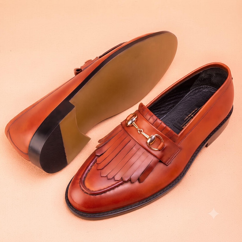 Handmade brown leather fringe loafers for men with metal bit detail, premium slip-on formal dress shoes crafted from genuine leather for weddings and business wear.