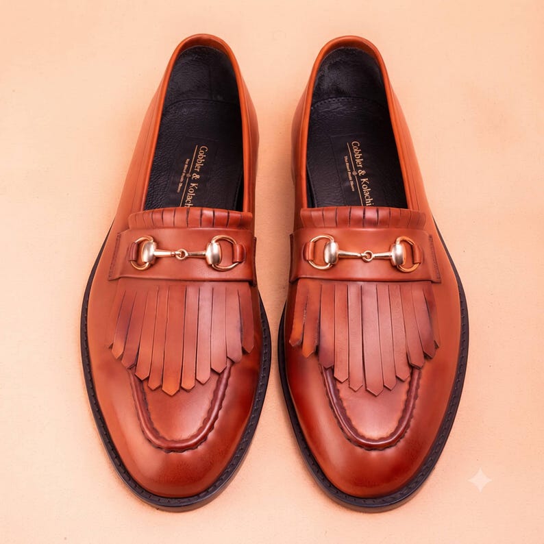 Handmade brown leather fringe loafers for men with metal bit detail, premium slip-on formal dress shoes crafted from genuine leather for weddings and business wear.