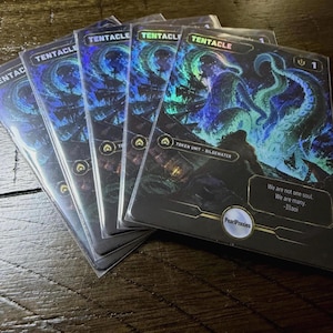 May include: A set of four holographic trading cards featuring a dark blue and green illustration of a giant tentacle rising from the sea. The cards display the text TENTACLE, TOKEN UNIT - BILGEWATER, and the quote We are not one soul. We are many. -Illaoi.