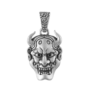 May include: A silver-colored pendant featuring a detailed Oni mask design. The pendant has curved horns, a wide grin with visible teeth, and intricate facial features. The bail has a decorative swirl pattern.
