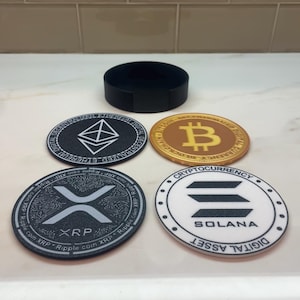 May include: A set of cryptocurrency-themed coasters. The coasters feature the logos for Ethereum, Bitcoin, XRP, and Solana. A black coaster holder is also included. The coasters are round and have a white or black background with the cryptocurrency logos.