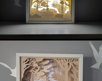 Könnte beinhalten: Ein gerahmtes Papierkunstwerk, das eine geschichtete Waldszene mit einem japanischen Torii-Tor und Bäumen darstellt. Das Kunstwerk befindet sich in einem weißen Rahmen, wobei die Papierschichten Tiefe und Schatten erzeugen. Die Farbpalette ist hauptsächlich beige und weiß.
