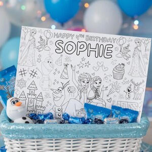 Pode incluir: Uma cesta de vime branca cheia de doces embrulhados em azul, uma pequena figura de Olaf e uma p&aacute;gina para colorir. A p&aacute;gina para colorir diz "HAPPY 4TH BIRTHDAY SOPHIE" e apresenta desenhos de personagens do filme Frozen.