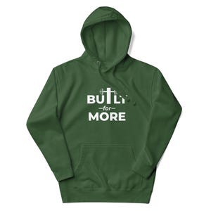 May include: A dark green hoodie with a front pocket and a hood with a drawstring. The front features the white text "BUILT for MORE" with a barbell and cross graphic. The hoodie is made of a soft material.