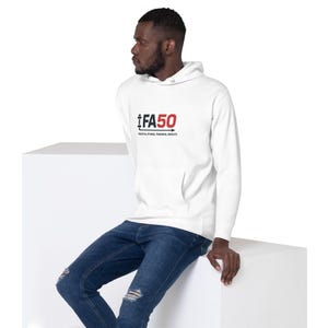 May include: A white hooded sweatshirt with a front pocket and the text "iFA50" in red and black. Below the text is the phrase "PRACTICAL FITNESS. POWERFUL RESULTS." The person in the image is wearing blue jeans.
