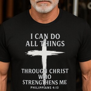 May include: Black t-shirt featuring the text "I CAN DO ALL THINGS THROUGH CHRIST WHO STRENGTHENS ME" and "PHILIPPIANS 4:13" in white, with a white cross graphic. The shirt has a crew neck design.