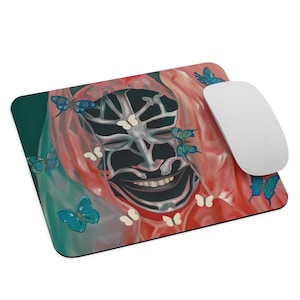 May include: A rectangular mousepad featuring a surreal design with a smiling face, butterflies, and a red and teal color scheme. A white computer mouse is placed on the right side of the mousepad.