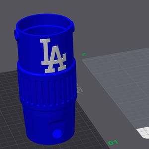 May include: A blue tumbler featuring a white "LA" logo, accompanied by several detached white components. The tumbler has a ridged lower section and a smooth upper section. The detached parts include a lid, a handle, and a small piece.