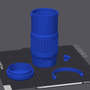 May include: A blue, cylindrical object with a ridged lower section, a removable lid, a curved handle, and a small, circular piece. The items are arranged on a dark surface with a grid pattern.