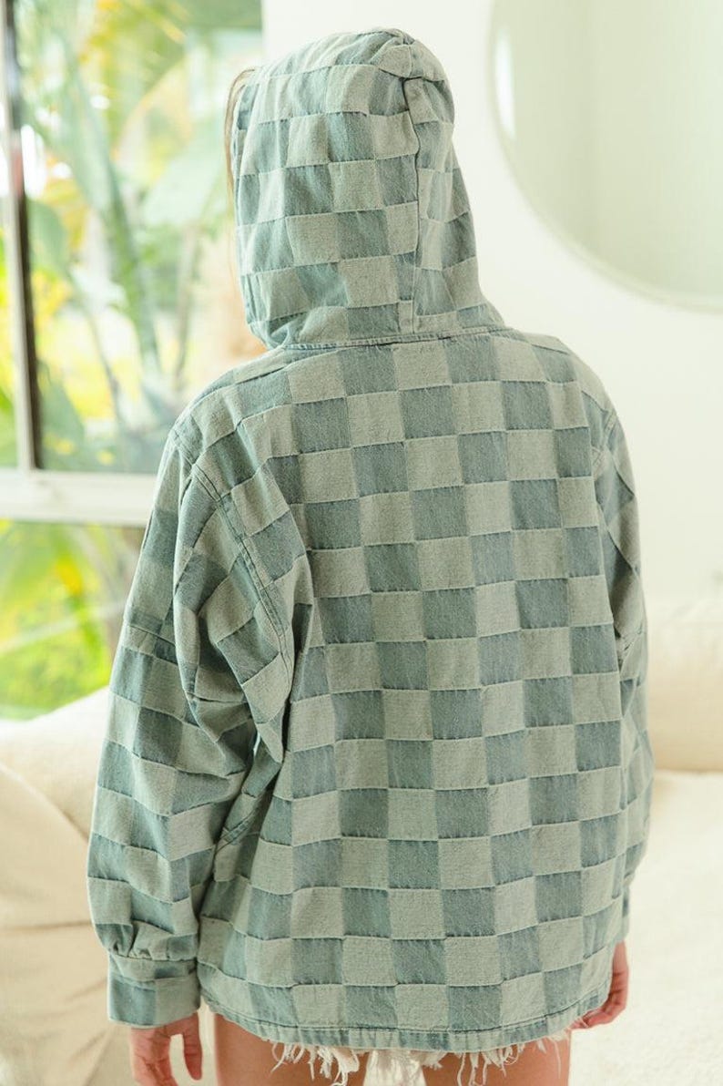 Lightweight denim hoodie with blue and gray checkered pattern, half-zip front, and drawstring hood—perfect for travel, weekend getaways, or road trip layering. Styled with frayed shorts for a relaxed, packable outfit. Keywords: travel hoodie, denim pullover, casual layers, wanderlust wardrobe, easy-to-style essentials.