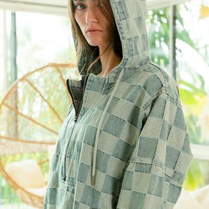 Denim checkered hoodie with half-zip front, drawstring hood, and relaxed fit—perfect for boho layering or festival outfits. Blue and gray tones pair beautifully with fringe, crochet, or embroidered accessories. Styled with frayed shorts for a carefree, music-festival-ready vibe. Keywords: bohemian hoodie, desert chic, wanderlust fashion, artisan denim.