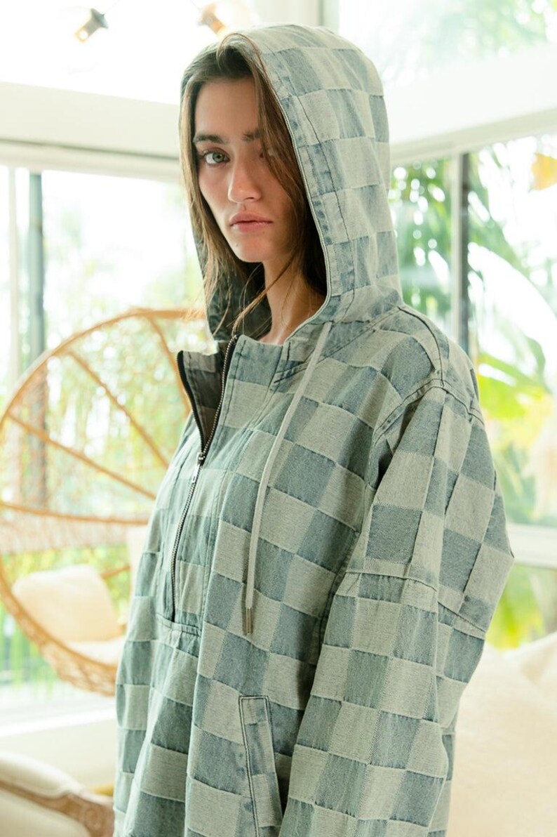 Denim checkered hoodie with half-zip front, drawstring hood, and relaxed fit—perfect for boho layering or festival outfits. Blue and gray tones pair beautifully with fringe, crochet, or embroidered accessories. Styled with frayed shorts for a carefree, music-festival-ready vibe. Keywords: bohemian hoodie, desert chic, wanderlust fashion, artisan denim.