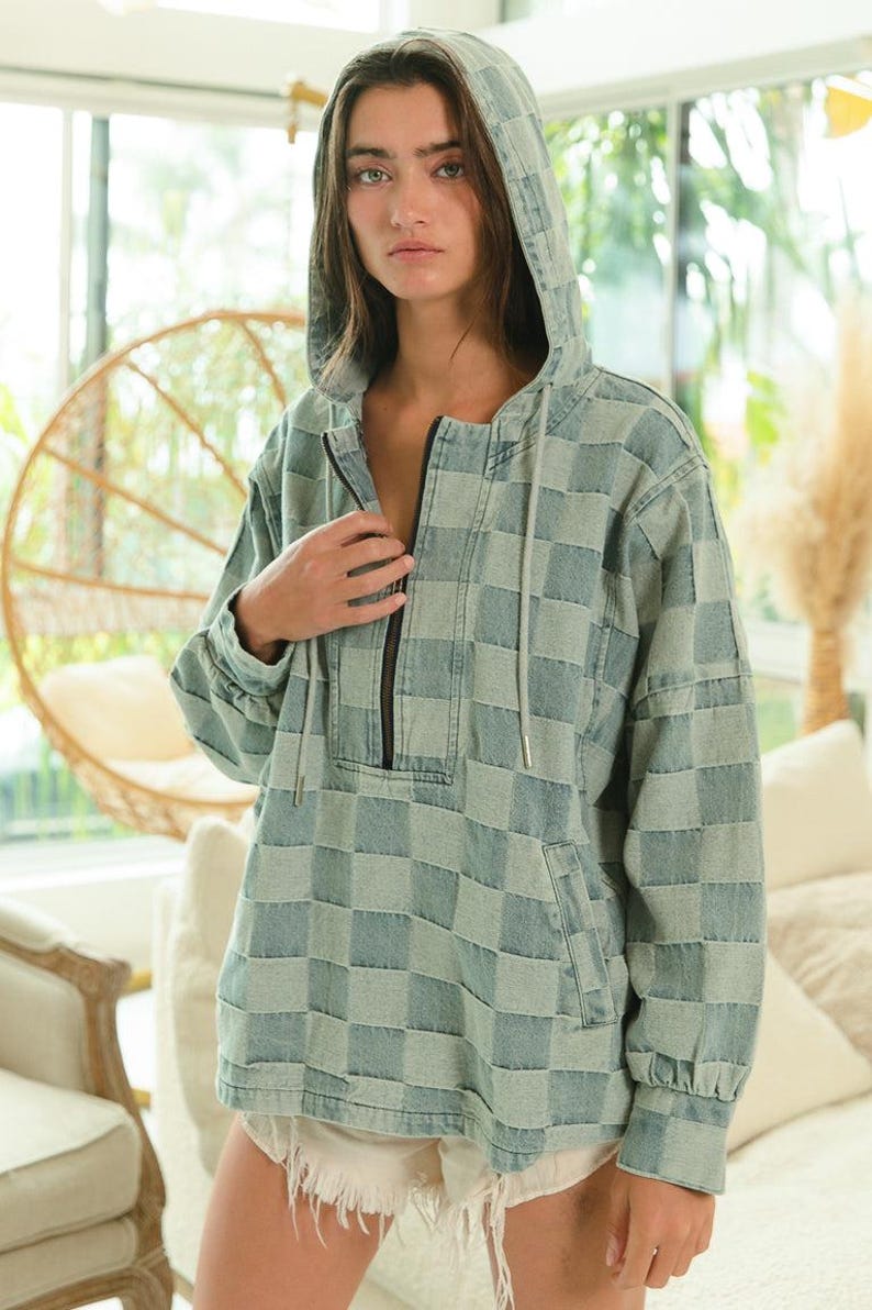 Soft denim checkered hoodie in muted blue and gray tones, perfect for coastal granddaughter style or cottagecore layering. Features a half-zip front, drawstring hood, and kangaroo pocket. Lightweight denim pullover ideal for breezy mornings, beach walks, or cozy porch lounging. Styled with frayed white shorts for a relaxed, feminine vibe. Great for soft textures, neutral palettes, and slow fashion lovers.