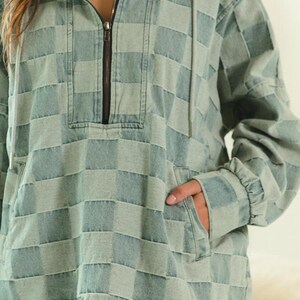 Blue-gray checkered denim hoodie with half-zip front and drawstring hood, styled with frayed shorts for a modern preppy twist. Perfect for back-to-school looks, campus layering, or academic chic. Great with loafers, pleated skirts, or oversized totes. Keywords: preppy hoodie, collegiate fashion, smart casual, soft denim layers.