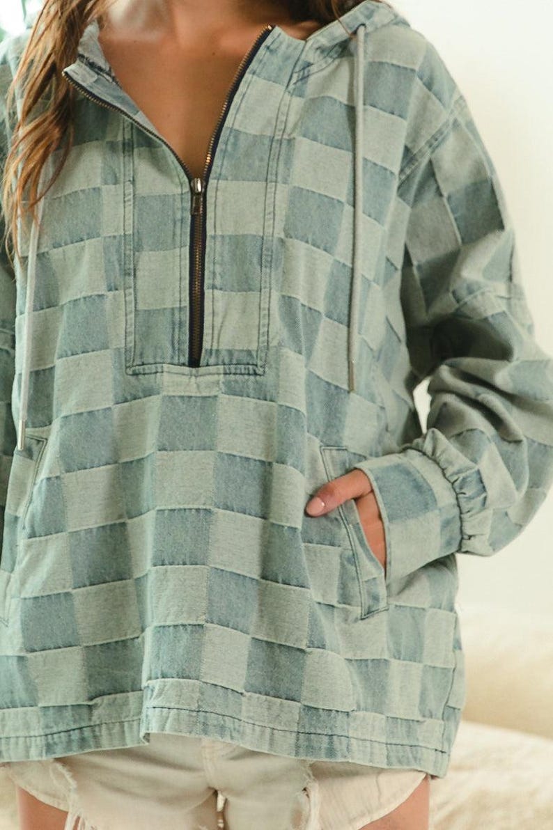 Blue-gray checkered denim hoodie with half-zip front and drawstring hood, styled with frayed shorts for a modern preppy twist. Perfect for back-to-school looks, campus layering, or academic chic. Great with loafers, pleated skirts, or oversized totes. Keywords: preppy hoodie, collegiate fashion, smart casual, soft denim layers.