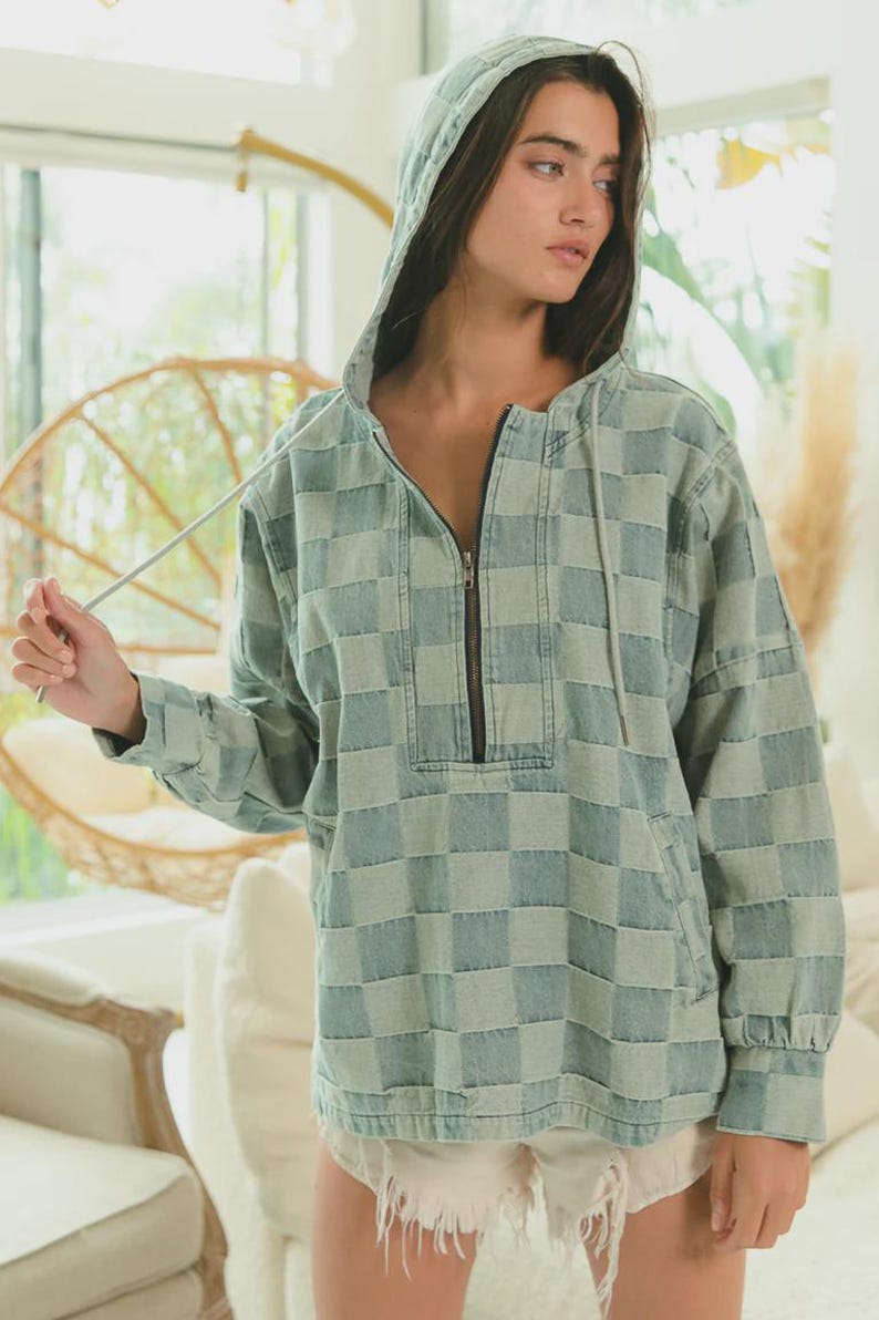 Blue-gray denim hoodie with a woven checkered pattern, channeling western casual and Americana vibes. Half-zip pullover with drawstring hood and front pocket, styled with frayed hem shorts. Perfect for rodeo nights, country concerts, or rustic weekend getaways. A modern take on vintage western wear—great for layering with boots, hats, and turquoise accessories.