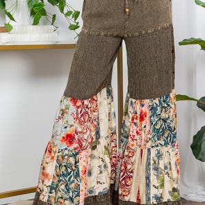May include: Olive green palazzo trousers with a drawstring waist and floral patchwork design. The trousers feature a wide leg with a floral print and a lace trim at the hem. The fabric has a textured appearance.