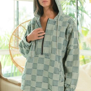 Muted blue-gray checkered hoodie in soft denim, featuring a clean half-zip front and minimalist silhouette. Ideal for neutral chic, capsule wardrobe, or minimalist fashion lovers. Lightweight and breathable—perfect for transitional seasons. Styled with white frayed shorts for a crisp, effortless look. Keywords: tonal layering, soft neutrals, quiet luxury, elevated basics.