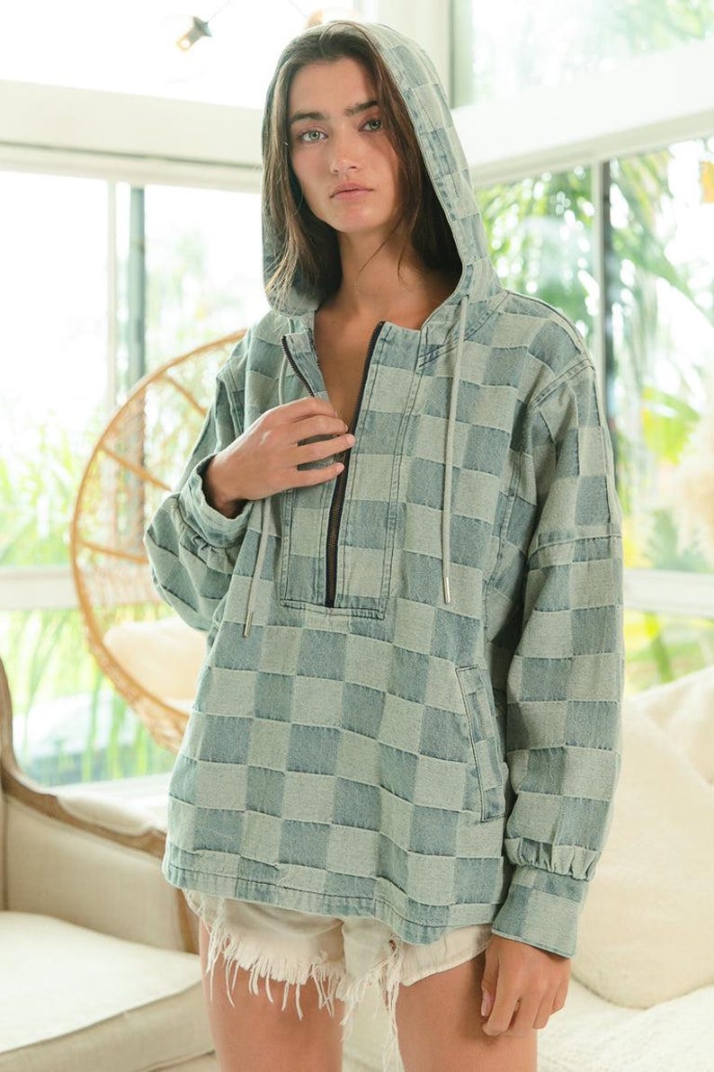 Muted blue-gray checkered hoodie in soft denim, featuring a clean half-zip front and minimalist silhouette. Ideal for neutral chic, capsule wardrobe, or minimalist fashion lovers. Lightweight and breathable—perfect for transitional seasons. Styled with white frayed shorts for a crisp, effortless look. Keywords: tonal layering, soft neutrals, quiet luxury, elevated basics.